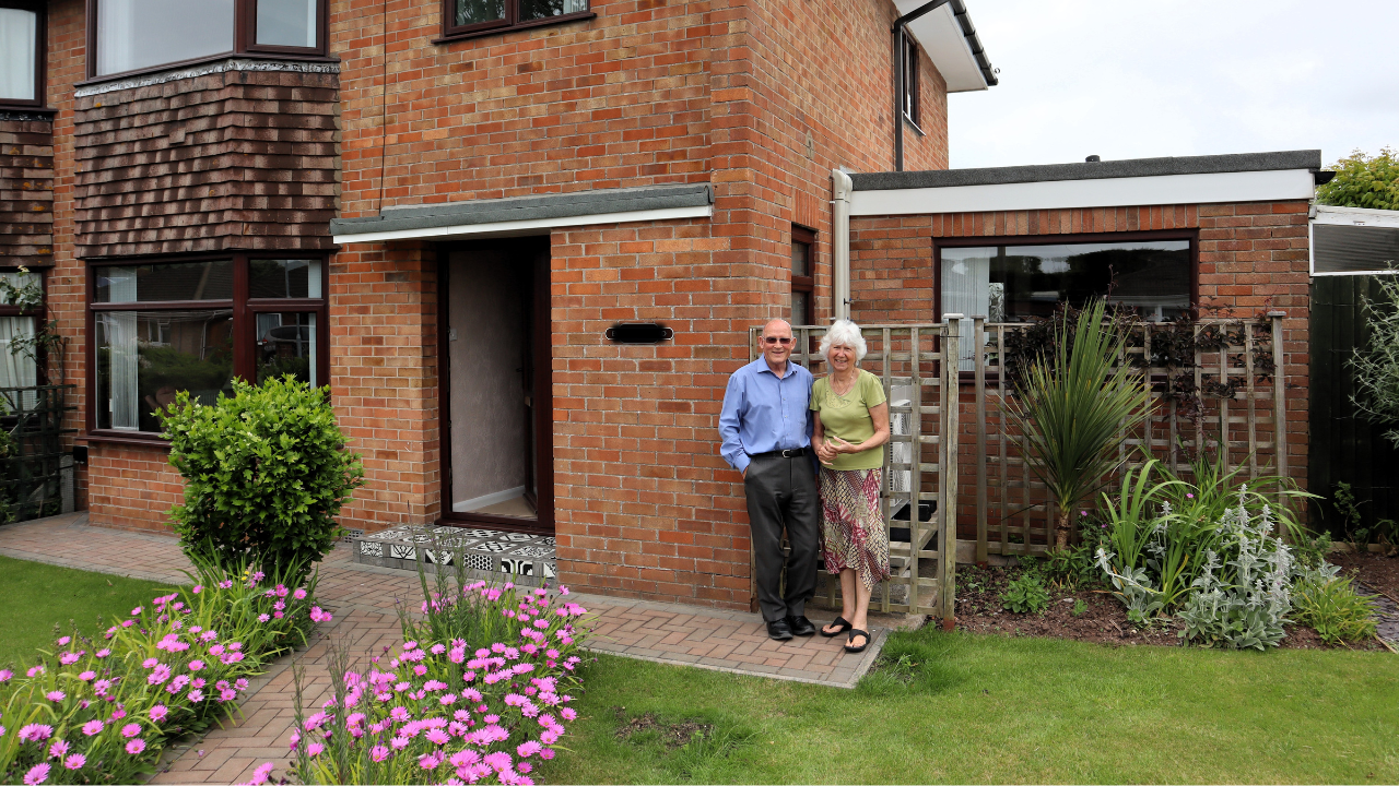 Clive and his wife standing outside their home.